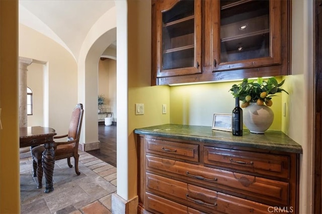1470 Via Chaparral, Fallbrook, CA 92028 - kitchen featuring arched walkways, glass insert cabinets, light stone finish floors, vaulted ceiling, and baseboards