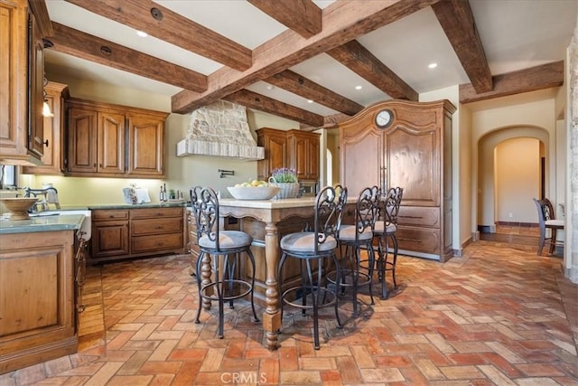 1470 Via Chaparral, Fallbrook, CA 92028 - kitchen featuring arched walkways, a breakfast bar, a kitchen island, beamed ceiling, and brick floors