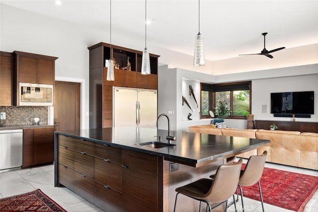 3386 Canyon Oaks Ter, Chico, CA 95928 - kitchen with a sink, built in appliances, dark countertops, a center island with sink, and a breakfast bar area