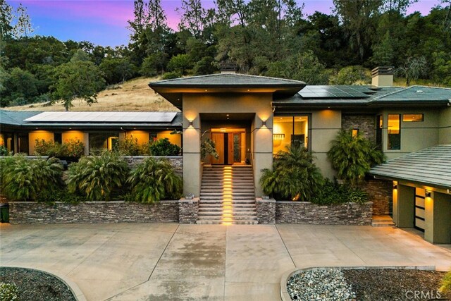 3386 Canyon Oaks Ter, Chico, CA 95928 - prairie-style house with stucco siding, roof mounted solar panels, a chimney, and stone siding