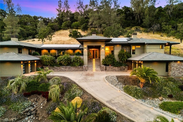 3386 Canyon Oaks Ter, Chico, CA 95928 - prairie-style home with solar panels, a chimney, curved driveway, and stucco siding