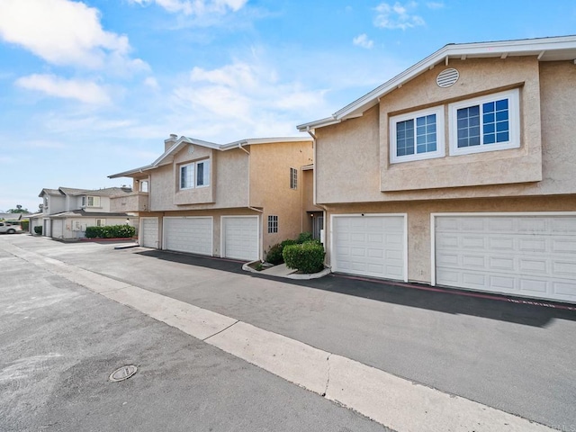 1465 E Lexington Ave Unit 11C, El Cajon, CA 92019 - view of property with stucco siding, a garage, and a residential view