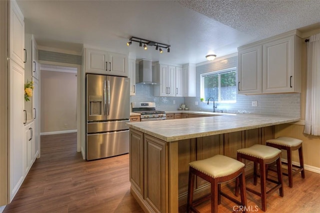 6125 Desabla Ln, Magalia, CA 95954 - kitchen featuring stainless steel appliances, wall chimney exhaust hood, a peninsula, light countertops, and light wood-style flooring