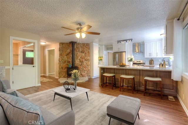 6125 Desabla Ln, Magalia, CA 95954 - living room featuring a wood stove, a textured ceiling, light wood finished floors, and ceiling fan