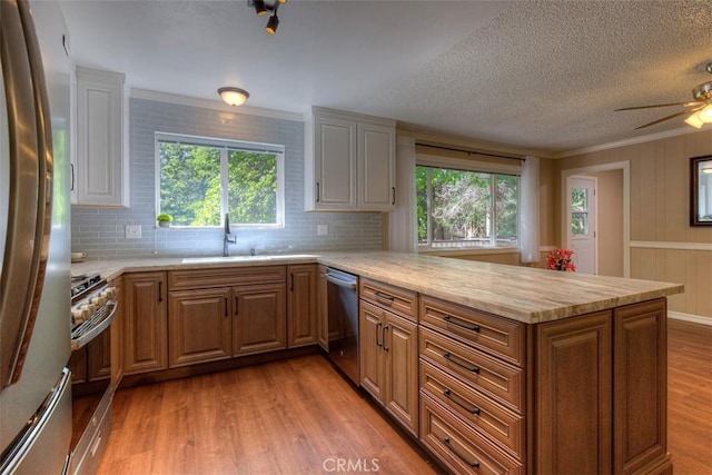 6125 Desabla Ln, Magalia, CA 95954 - kitchen with stainless steel appliances, a peninsula, light wood-style floors, a sink, and backsplash