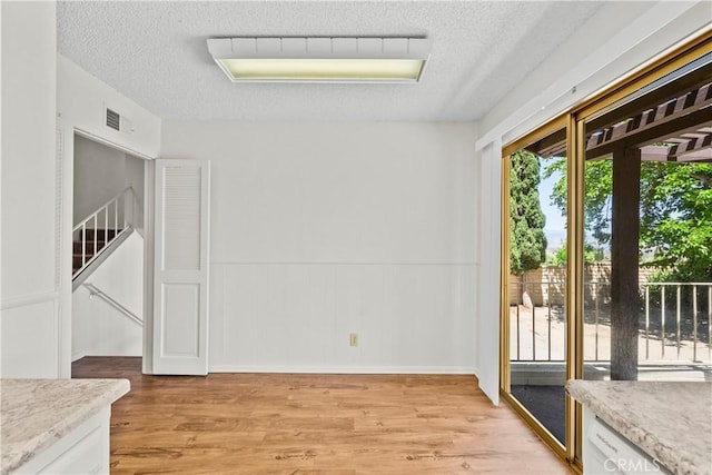 19627 Goldstream Way, Newhall, CA 91321 - unfurnished room featuring light wood-style flooring, a textured ceiling, and wainscoting
