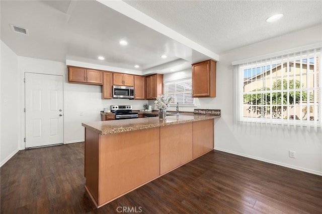1418 E Wilshire Ave, Fullerton, CA 92831 - kitchen with appliances with stainless steel finishes, a peninsula, brown cabinetry, dark wood-type flooring, and recessed lighting