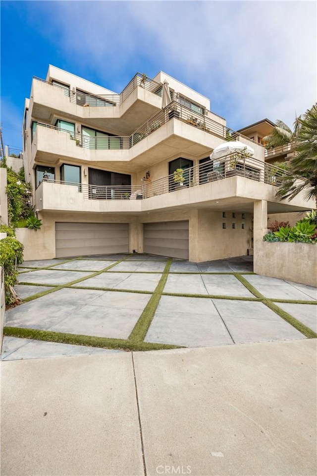 151 Cedar Way, Laguna Beach, CA 92651 - view of front of property with concrete driveway, an attached garage, stucco siding, and a balcony