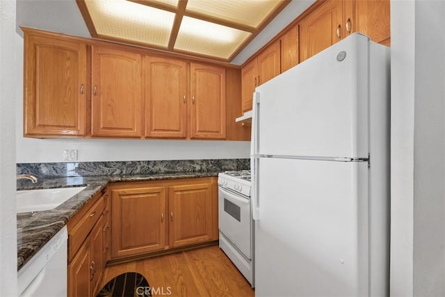 17152 Pacific Coast Unit 19, Huntington Beach, CA 92649 - kitchen with white appliances, a sink, light wood-style flooring, under cabinet range hood, and dark stone counters