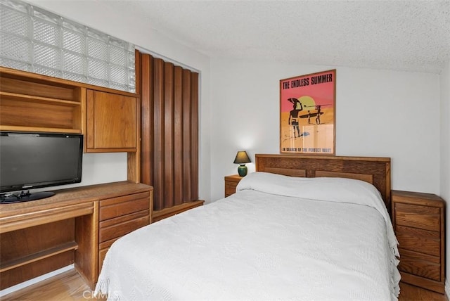 17152 Pacific Coast Unit 19, Huntington Beach, CA 92649 - bedroom with vaulted ceiling, light wood-style floors, and a textured ceiling