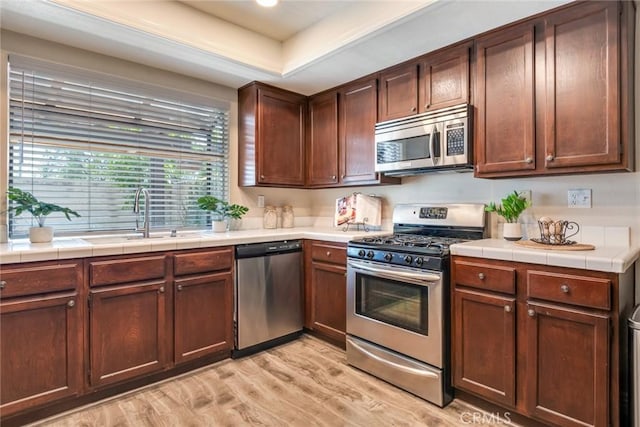2209 E Badillo St, Covina, CA 91724 - kitchen featuring appliances with stainless steel finishes, a sink, light wood-type flooring, and tile counters