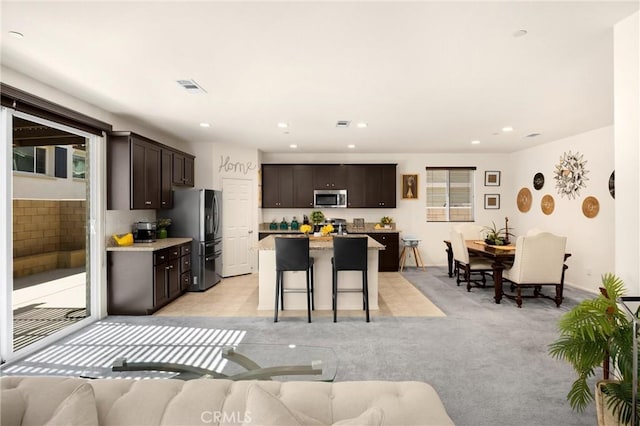 4337 Rima Dr, Fontana, CA 92336 - kitchen with appliances with stainless steel finishes, dark brown cabinetry, open floor plan, a breakfast bar area, and a center island
