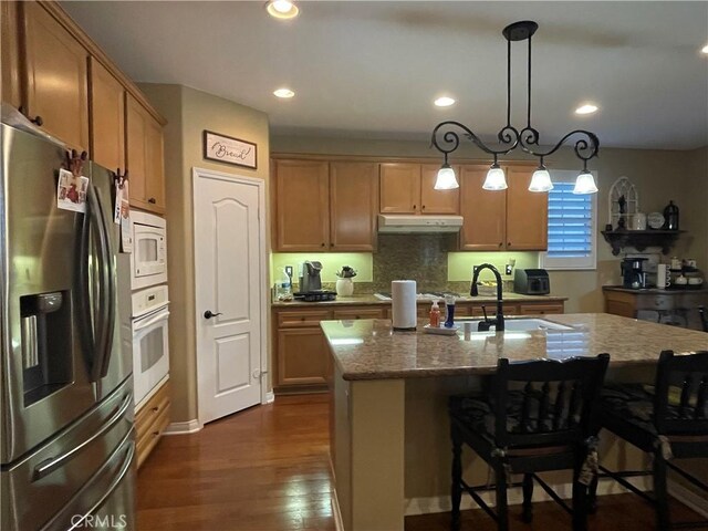 27665 Bottle Brush Way, Murrieta, CA 92562 - kitchen featuring white appliances, light stone counters, a sink, under cabinet range hood, and a kitchen bar