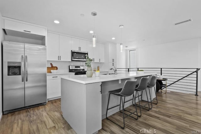 41361/2 Normal Ave Unit 1/2, Los Angeles, CA 90029 - kitchen with appliances with stainless steel finishes, white cabinetry, wood finished floors, light countertops, and recessed lighting