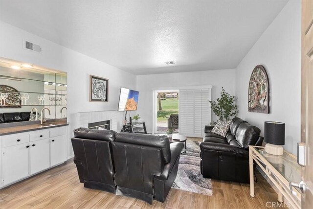 491 Desert Falls Dr N, Palm Desert, CA 92211 - living room with light wood-style flooring, a brick fireplace, and bar with sink