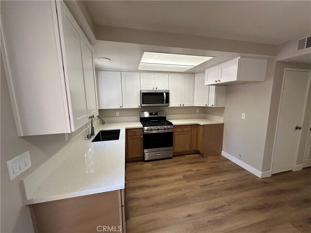 2394 Gonzaga Ln, Riverside, CA 92507 - kitchen featuring appliances with stainless steel finishes, light wood-style flooring, light stone countertops, and white cabinets