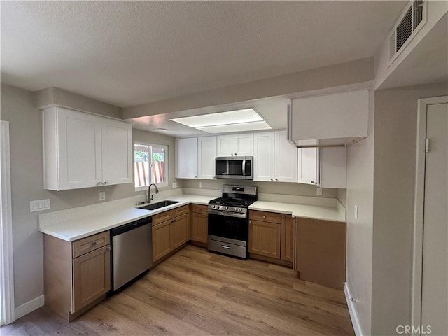 2394 Gonzaga Ln, Riverside, CA 92507 - kitchen with appliances with stainless steel finishes, light countertops, light wood-style flooring, white cabinets, and a textured ceiling