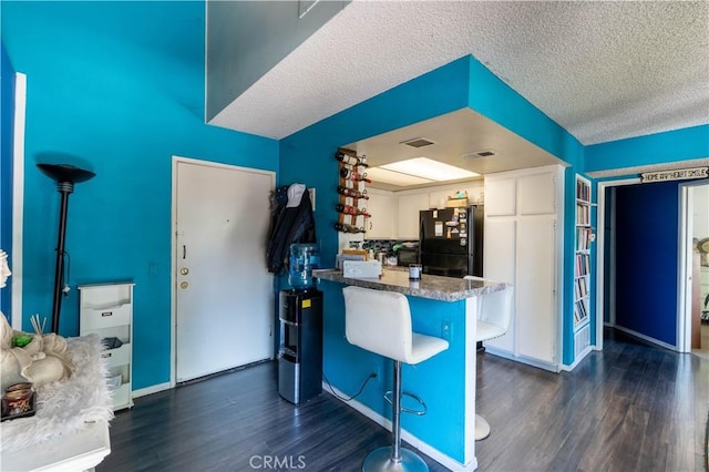 320 W Walnut St Unit 6, Ontario, CA 91762 - kitchen featuring freestanding refrigerator, dark wood-type flooring, white cabinetry, a breakfast bar, and a textured ceiling