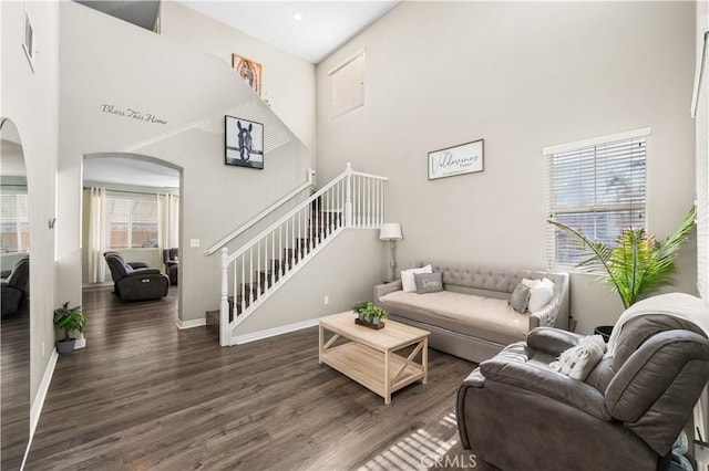 3116 Perdot Ave, Rosamond, CA 93560 - living area featuring arched walkways, a high ceiling, dark wood-style flooring, stairway, and baseboards