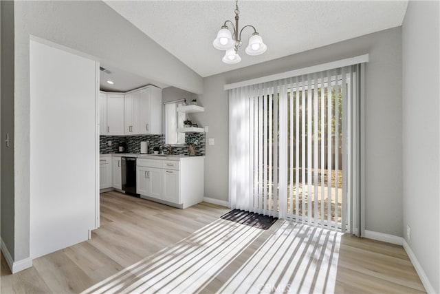 43638 Oleander St, Lancaster, CA 93535 - kitchen with black dishwasher, light wood-style floors, white cabinets, a chandelier, and lofted ceiling