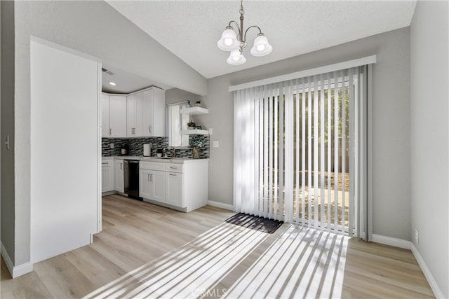 43638 Oleander St, Lancaster, CA 93535 - kitchen with black dishwasher, light wood-style flooring, white cabinetry, a chandelier, and lofted ceiling