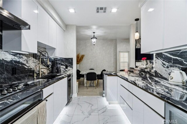 10659 Bloomfield St, Toluca Lake, CA 91602 - kitchen with wall chimney range hood, black oven, white cabinets, dark stone counters, and light marble finish flooring