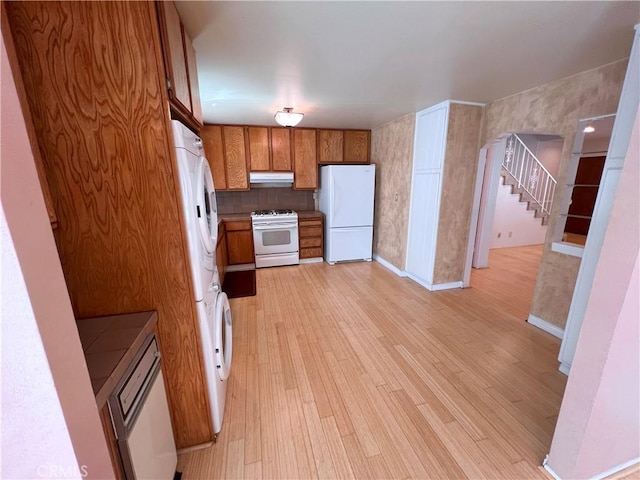 1509 E 23rd St Unit A, Signal Hill, CA 90755 - kitchen with white appliances, brown cabinets, light wood finished floors, under cabinet range hood, and estacked washer and dryer
