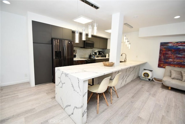 7309 Franklin Ave Unit 105, Los Angeles, CA 90046 - kitchen featuring black fridge, stainless steel microwave, light wood-type flooring, a peninsula, and a sink