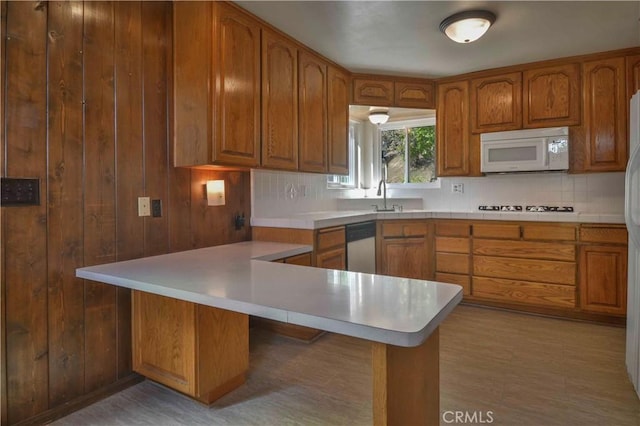 28680 Zion Dr, Lake Arrowhead, CA 92352 - kitchen with white microwave, decorative backsplash, brown cabinets, a peninsula, and light countertops