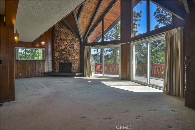 28680 Zion Dr, Lake Arrowhead, CA 92352 - unfurnished living room with carpet, a stone fireplace, wood walls, high vaulted ceiling, and wood ceiling with exposed beams