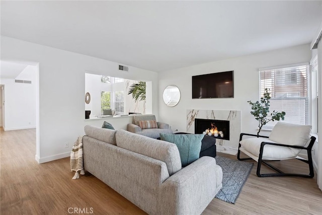 24775 Calle Serranona, Calabasas, CA 91302 - living room with healthy amount of natural light, light wood-style flooring, a premium fireplace, and baseboards