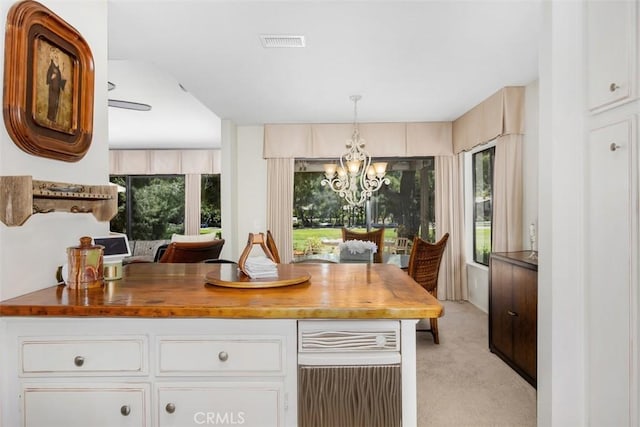 4119 Oak Island Ln, Fallbrook, CA 92028 - kitchen with butcher block countertops, a chandelier, light colored carpet, white cabinetry, and pendant lighting