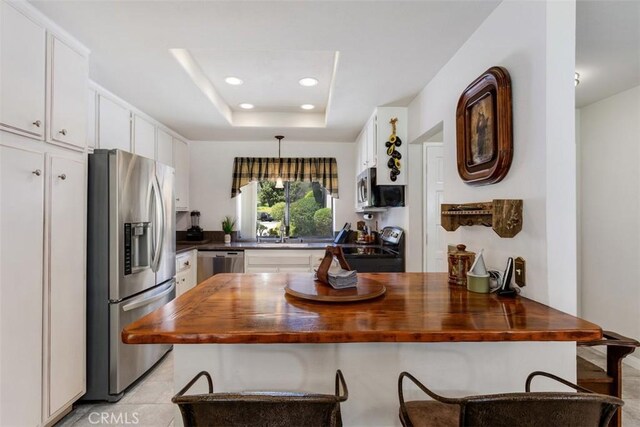 4119 Oak Island Ln, Fallbrook, CA 92028 - kitchen with stainless steel appliances, butcher block counters, white cabinets, recessed lighting, and a kitchen bar