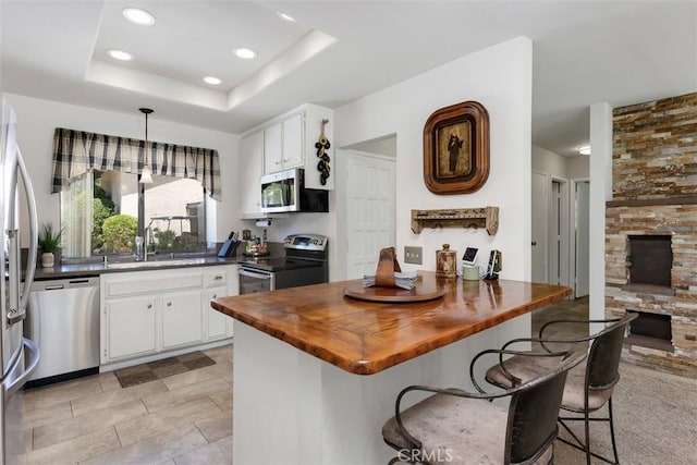 4119 Oak Island Ln, Fallbrook, CA 92028 - kitchen with appliances with stainless steel finishes, wooden counters, white cabinetry, a tray ceiling, and recessed lighting