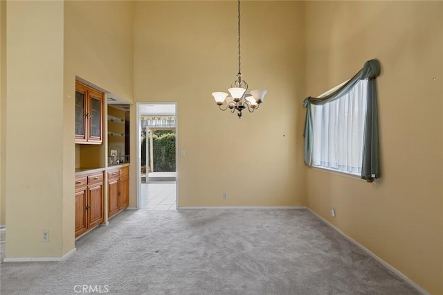 1713 Roanoke St, Placentia, CA 92870 - unfurnished dining area featuring light colored carpet, a chandelier, a high ceiling, and baseboards