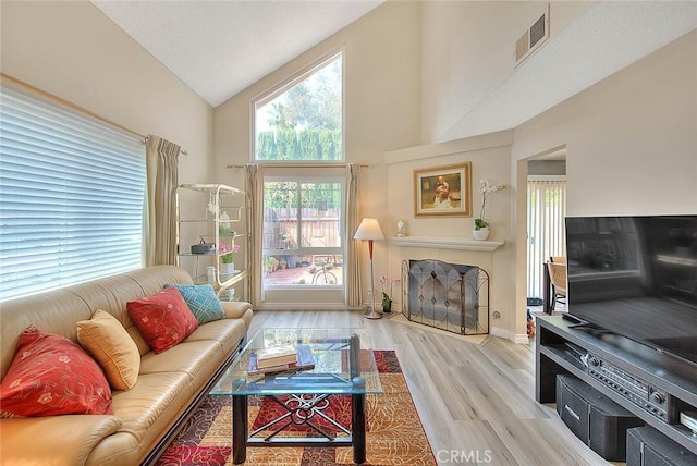 1189 N Sunflower Ave, Covina, CA 91724 - living room featuring wood finished floors, high vaulted ceiling, a tiled fireplace, and baseboards