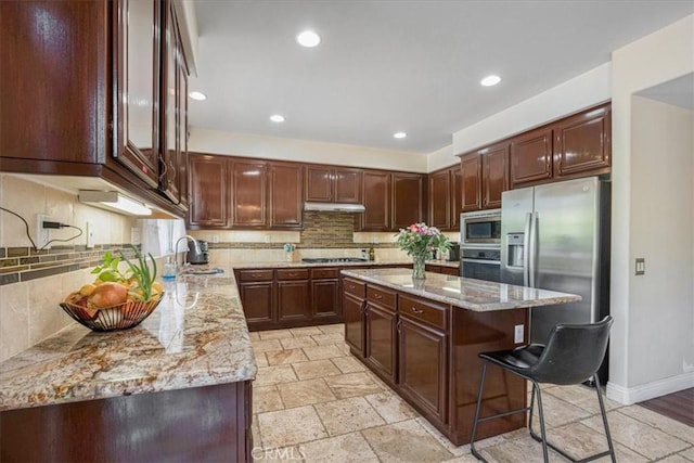 12614 Torrey Pine Rd, Moreno Valley, CA 92555 - kitchen featuring appliances with stainless steel finishes, a sink, light stone counters, stone tile flooring, and a center island