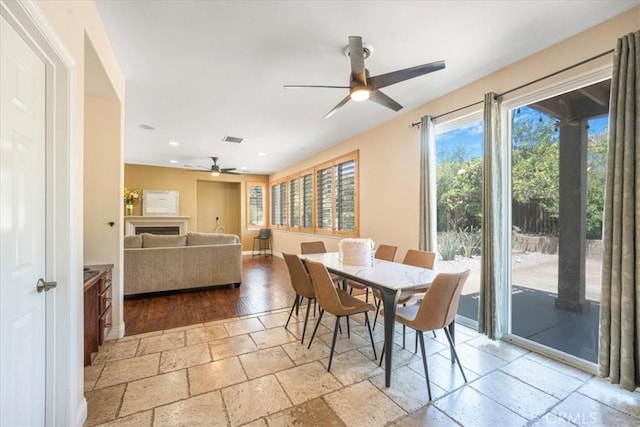 12614 Torrey Pine Rd, Moreno Valley, CA 92555 - dining space featuring ceiling fan, stone tile flooring, recessed lighting, a fireplace, and baseboards