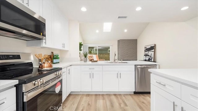 19029 Pires Ave, Cerritos, CA 90703 - kitchen with appliances with stainless steel finishes, a sink, light countertops, white cabinetry, and a peninsula