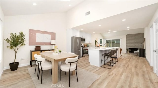 19029 Pires Ave, Cerritos, CA 90703 - dining area featuring light wood-style flooring, recessed lighting, baseboards, high vaulted ceiling, and a fireplace