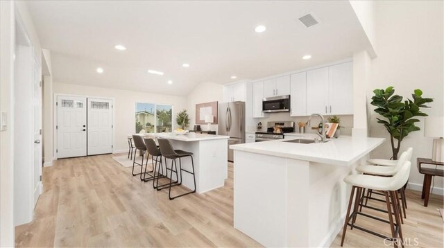 19029 Pires Ave, Cerritos, CA 90703 - kitchen featuring appliances with stainless steel finishes, a sink, a breakfast bar area, a kitchen island, and white cabinets