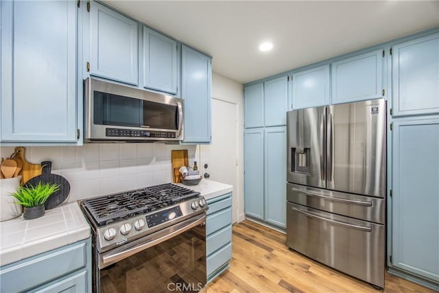 1456 Fernwood Dr, Redlands, CA 92374 - kitchen featuring appliances with stainless steel finishes, tile counters, blue cabinets, and recessed lighting