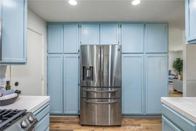 1456 Fernwood Dr, Redlands, CA 92374 - kitchen featuring stainless steel fridge with ice dispenser, tile countertops, light wood-style floors, recessed lighting, and range