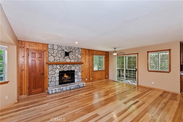 23819 Scenic Dr, Crestline, CA 92325 - unfurnished living room with wood finished floors, a stone fireplace, ceiling fan, wood walls, and baseboards