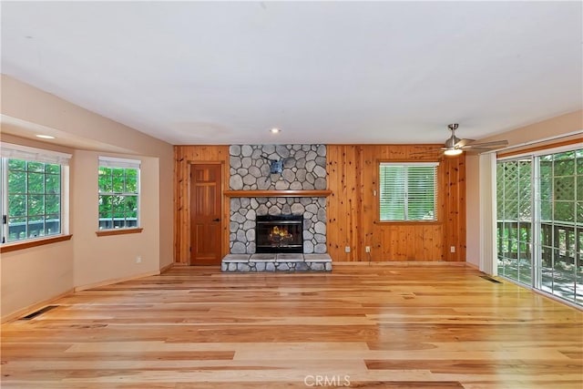 23819 Scenic Dr, Crestline, CA 92325 - unfurnished living room featuring wood finished floors, a stone fireplace, ceiling fan, baseboards, and wooden walls