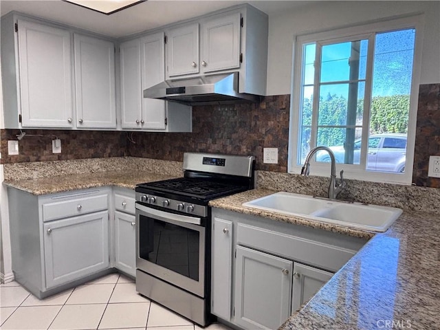 9900 Tagus St Unit 30, Pico Rivera, CA 90660 - kitchen featuring gas stove, under cabinet range hood, light tile patterned floors, a sink, and decorative backsplash