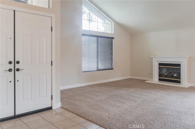 980 Creston Way, Beaumont, CA 92223 - unfurnished living room with light colored carpet, lofted ceiling, a glass covered fireplace, baseboards, and light tile patterned floors