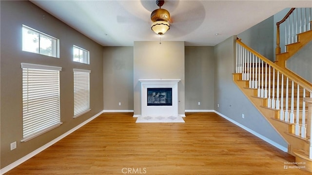4322 Waterside Ln, Oxnard, CA 93035 - unfurnished living room featuring a ceiling fan, light wood finished floors, stairs, a glass covered fireplace, and baseboards