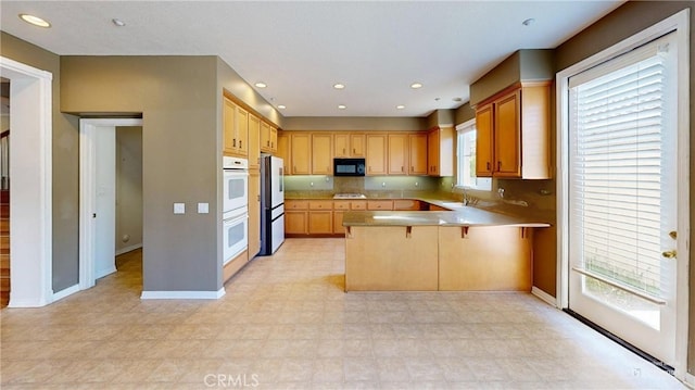 4322 Waterside Ln, Oxnard, CA 93035 - kitchen with black microwave, a peninsula, double oven, baseboards, and recessed lighting