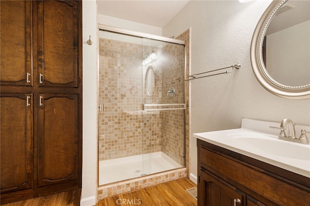 64 Rebie Way, Oroville, CA 95966 - bathroom featuring wood finished floors, a shower stall, vanity, and a textured wall